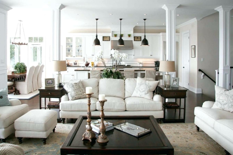 accogliente ed elegante salotto con divani bianchi tavolo quadrato con candelabri e cucina a vista
