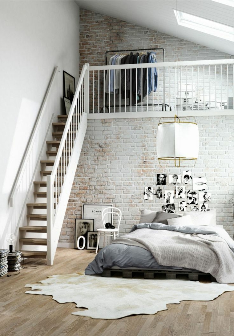 scala con soppalco mansardato con appendiabiti a vista, camera da letto con fotografie appese al muro con mattoni a vista