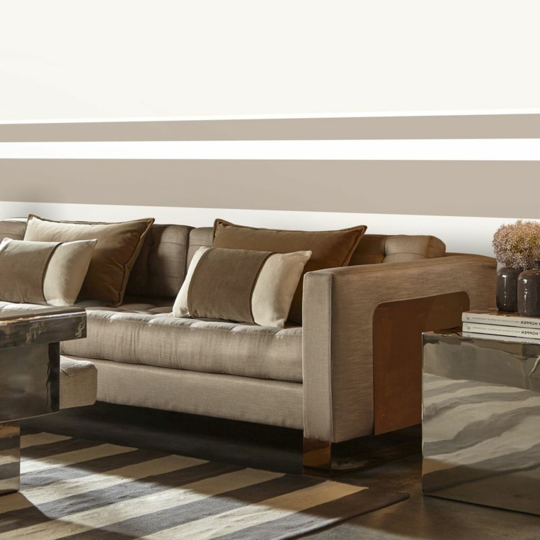 divano, cuscini e tappeto di una tonalità di colore tortora calda, parete a righe bianche e tortora