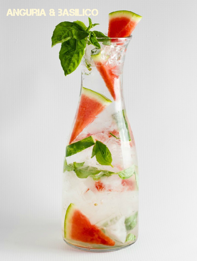 Acqua detox servita in una caraffa di vetro, bevanda a base di anguria e foglie di basilico 