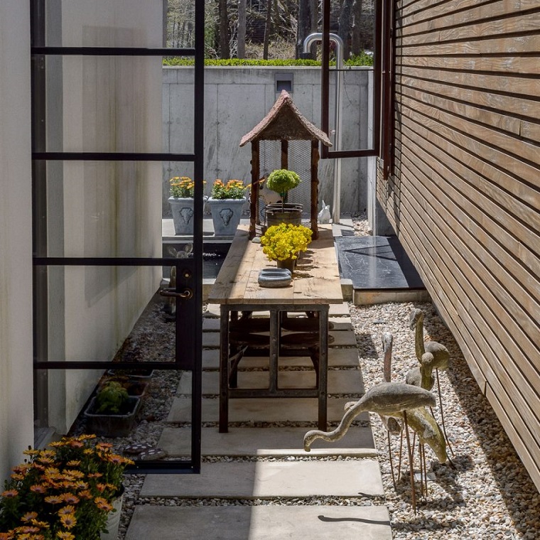 Arredamento di un giardino stretto e lungo con tavolo di legno e una doccia in metallo 