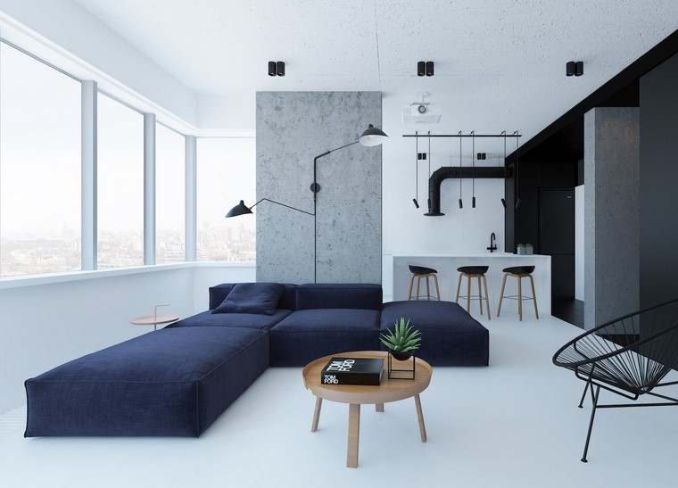 Open space cucina soggiorno e un divano di colore blu con penisola, tavolino rotondo in legno abbinato