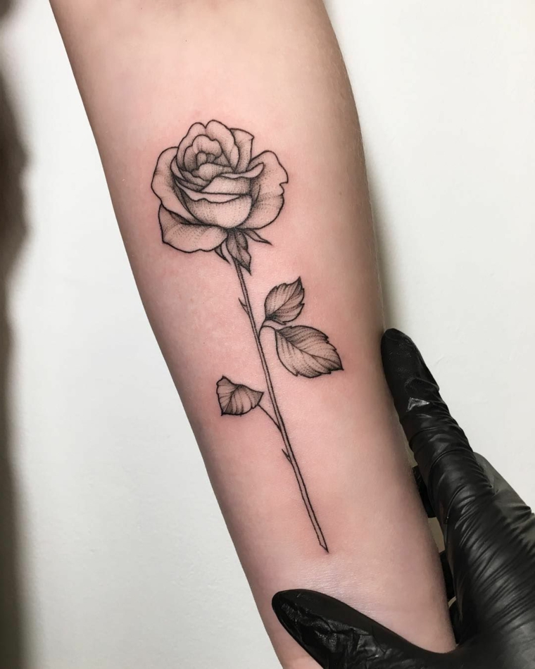 idea per tattoo femminili braccio, una rosa in bianco e nero stilizzata con un lungo gambo