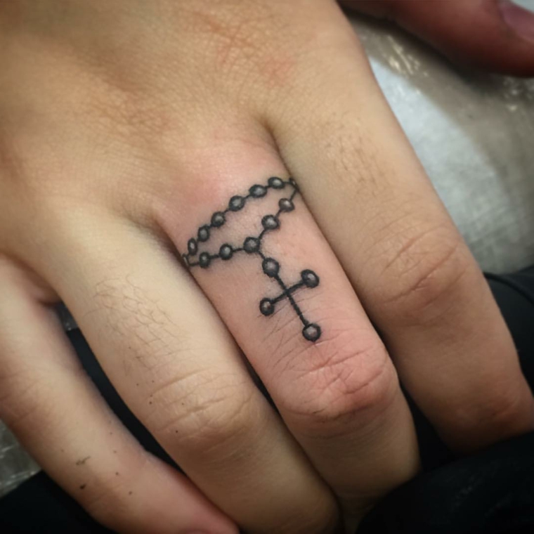 grazioso tattoo femminili piccoli, un rosario con la croce tatuato sul dito medio