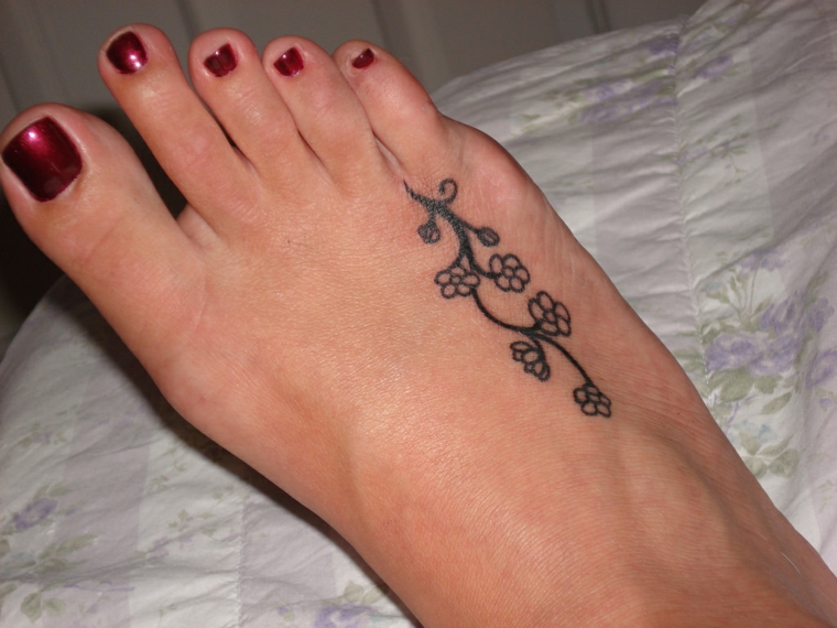 idea per tatuaggi particolari un ramo con dei fiorellini sulla parte esterna del piede