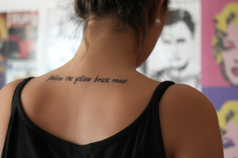schiena di una ragazza con i capelli raccolti, scritta sulla schiena idea per tatuaggi eleganti