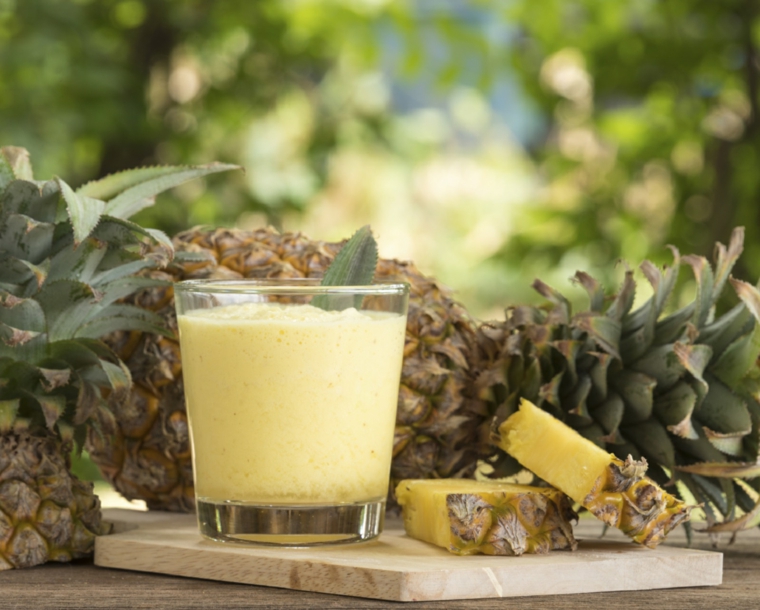 Bicchiere con un frullato di ananas e foglie di menta per conferire più gusto