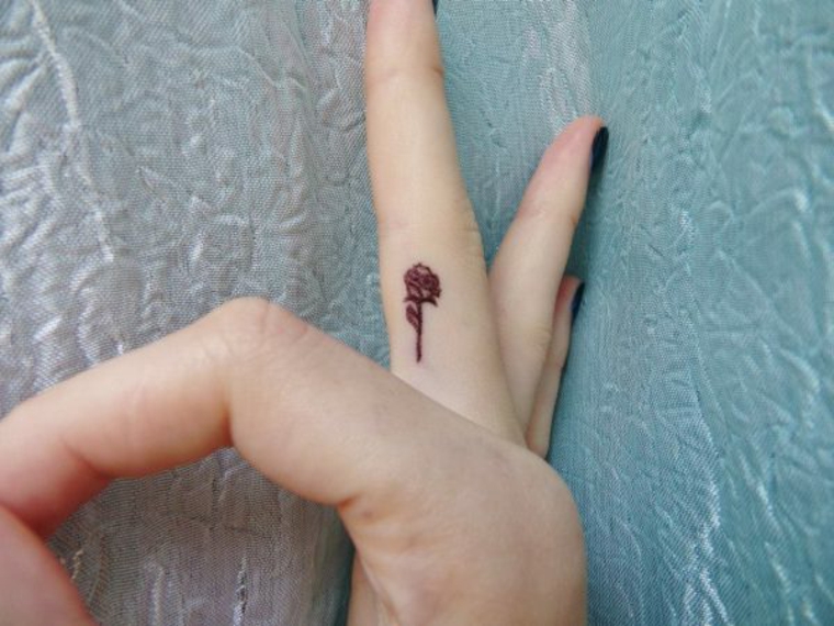 femminile proposta per tatuaggio rosa piccola rossa all'interno del dito medio