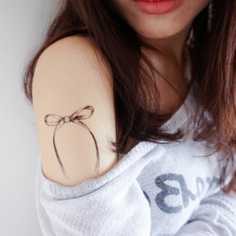 bellissimo fiocco con sfumature grigie sotto la spalla di una ragazza, idea piccoli tattoo femminili