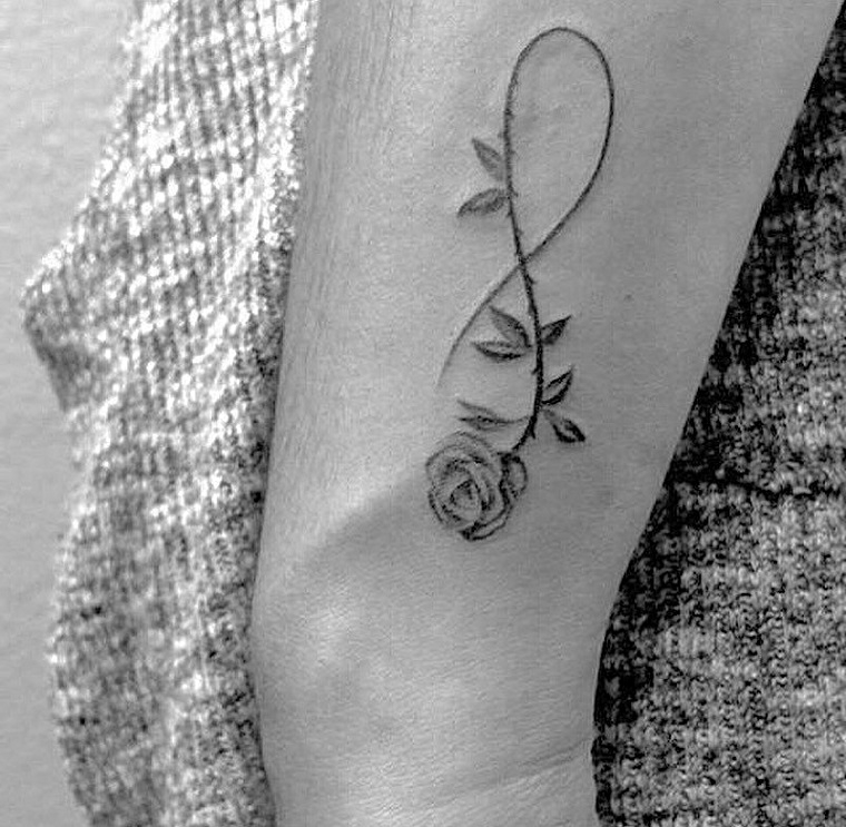 Simboli tattoo e un'idea con una rosa e il simbolo dell'infinito sul braccio di una donna