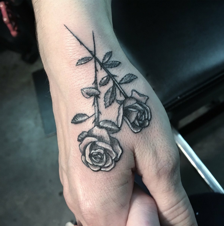 bellissima idea per un tattoo sulla mano, due rose di medie dimensioni con il gambo