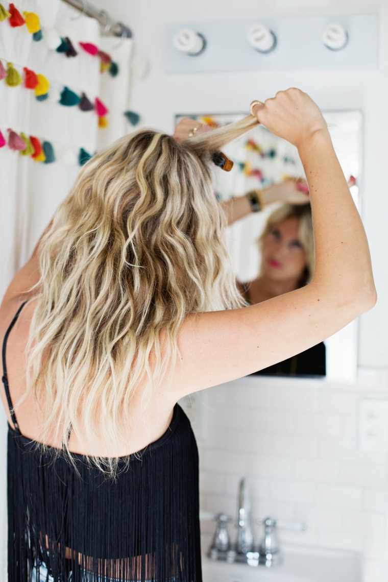 capelli biondi, ragazza davanti allo specchio che cotona i capelli come fare i capelli mossi naturali