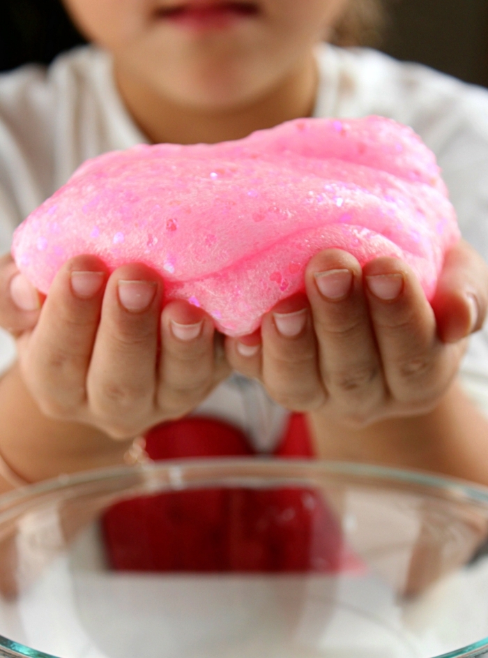 Bambina che gioca con lo slime di colore rosa glitter incorporati nell'impasto