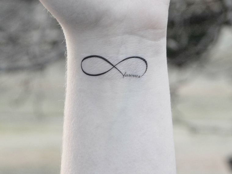 Tattoo infinito con scritta Forever, disegno tatuaggio sul polso della mano di una donna