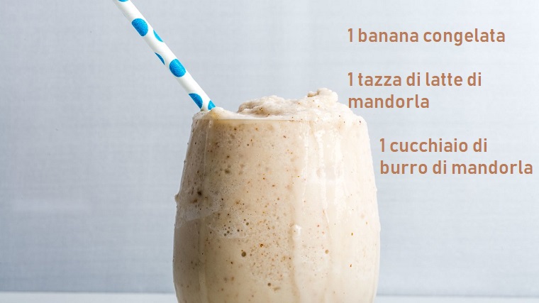 Bicchiere di vetro con uno smoothie alla banana e latte di mandorla servito cremoso con cannuccia