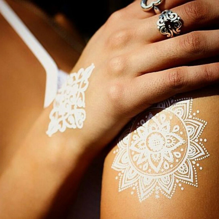 Fiore di loto tattoo significato, tatuaggio mandala di colore bianco sulla mano e sulla spalla di una donna