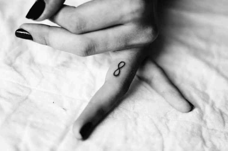 Simboli tattoo e un'idea con l'infinito tatuato sul dito anulare della mano di una donna