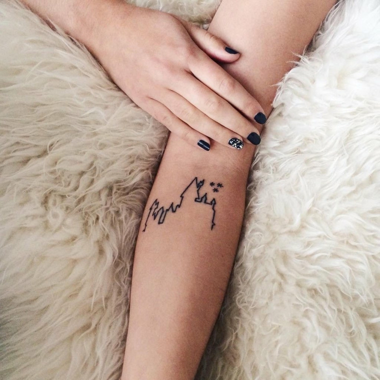 Un'idea per dei tatuaggi avambraccio di una donna con un piccolo disegno di una montagna con castello
