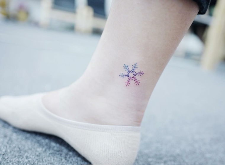 Tatuaggi alla caviglia femminili, disegno colorato di una un fiocco di neve sulla gamba di una donna
