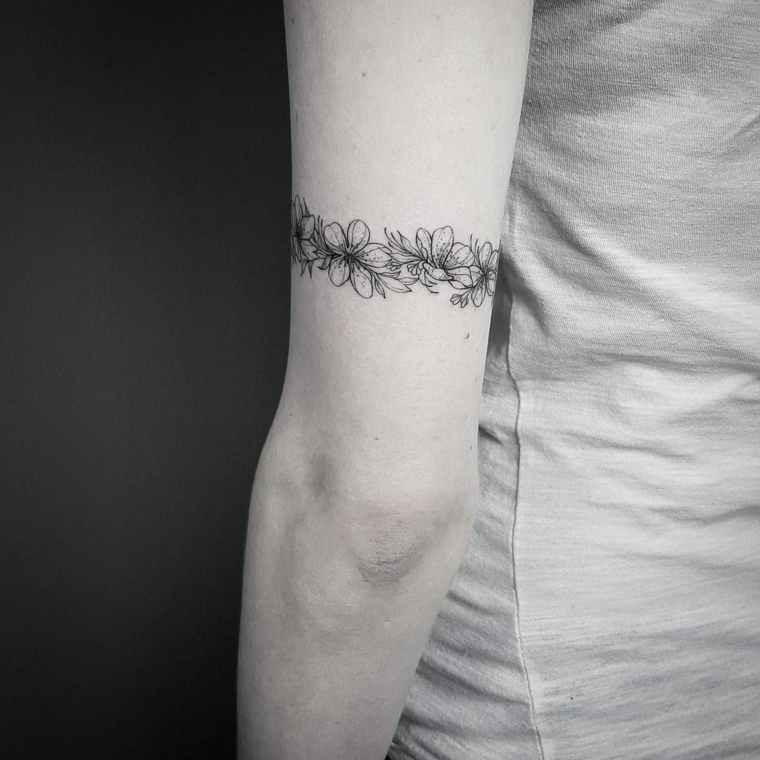 Idea per un tatuaggio bracciale sul bicipite di una donna, immagine bianco e nera di un tattoo