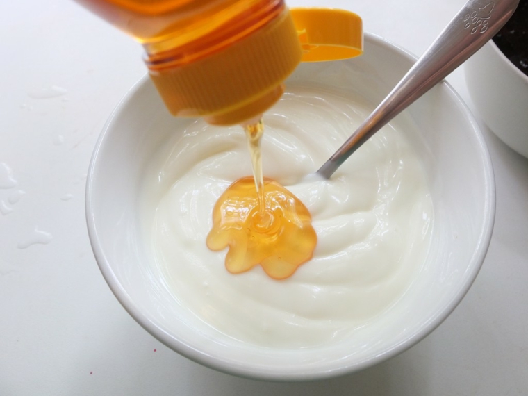 Scrub viso fatto in casa, ciotola con all'interno yogurt e miele versato dalla bottiglia