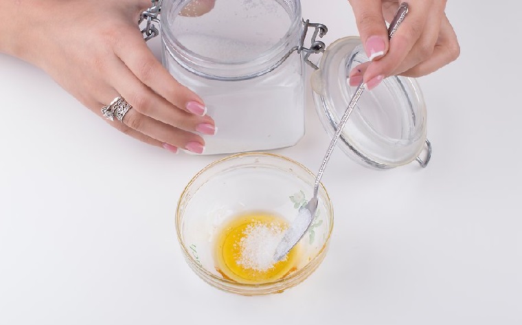 Come fare lo scrub con miele e zucchero, ingredienti in una ciotola di vetro mescolati con un cucchiaio