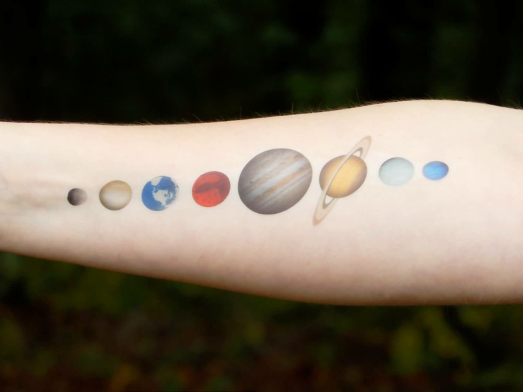 Il sistema solare colorato e tatuato sull'avambraccio di una donna 