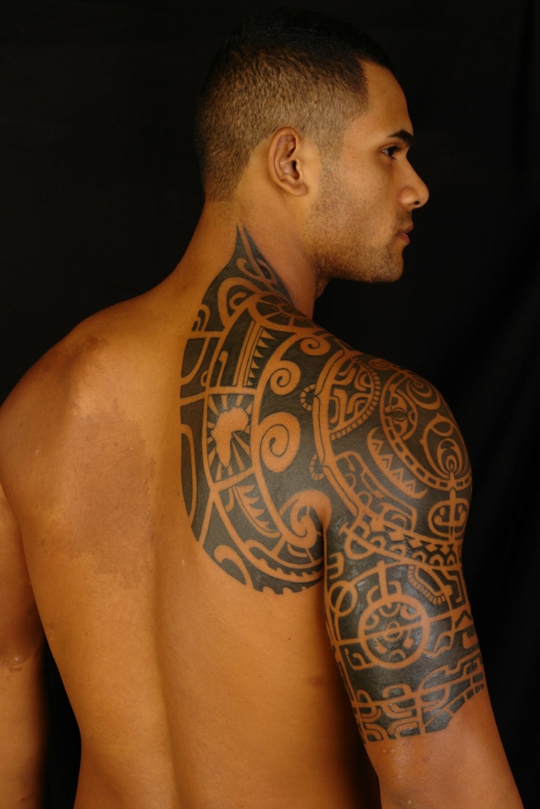 Un uomo con un tattoo maori sulla spalla e il bicipite, tatuaggio bracciale idee disegni
