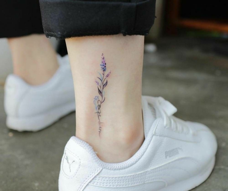 Scritta carpe diem sulla caviglia di una donna, tattoo stilizzati di colore viola e nero con fiore