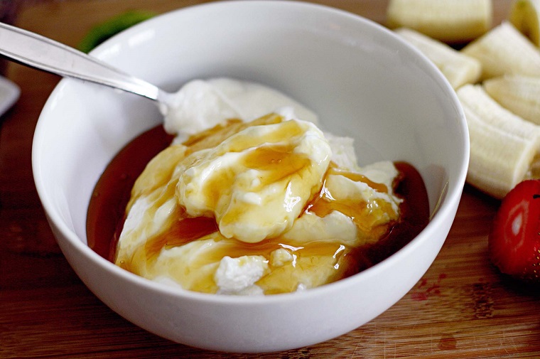 Dolci freddi veloci e una ciotola con yogurt e miele uniti insieme e mescolati con cucchiaio 