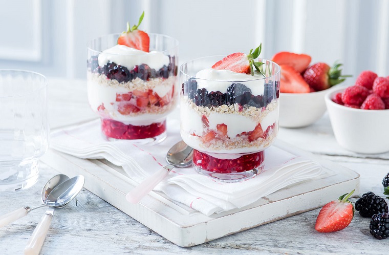 Esempio colazione sana e un'idea con dello yogurt bianco e frutti di bosco a strati in un bicchiere di vetro