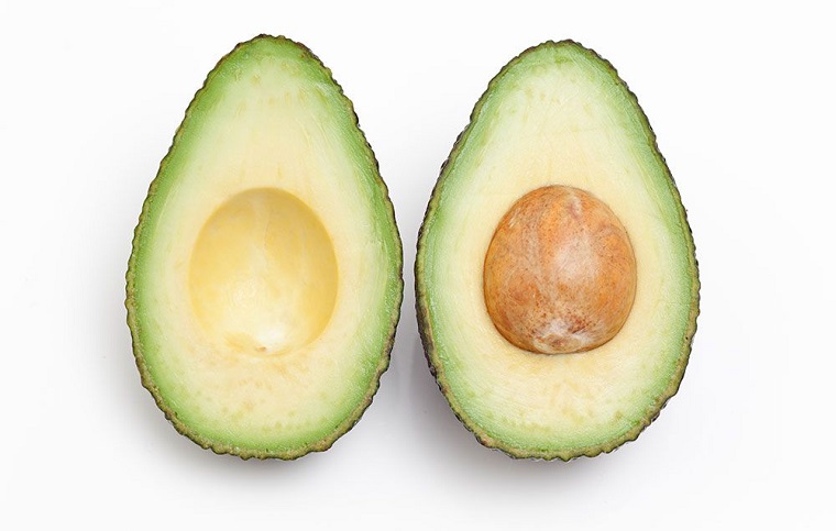 Dieta senza carboidrati e zuccheri mangiando avocado tagliato a metà con la noce