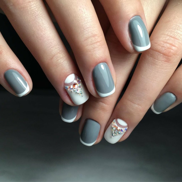 Unghie decorate con brillantini, french manicure inversa di colore bianco su una base di smalto grigio 