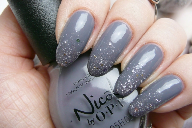 Nail art con delle unghie lunghe e uno smalto grigio con glitter di colore argento 