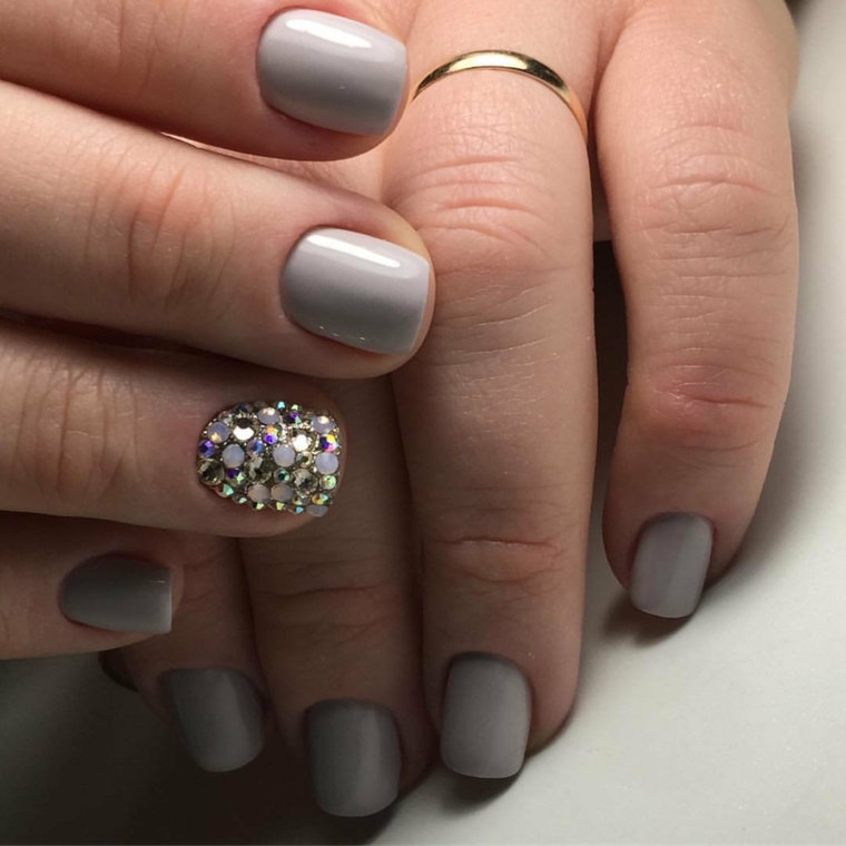 Accent nail con brillantini e unghie corte con uno smalto di colore grigio chiaro