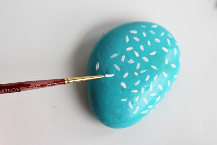 Attività innovative per decorare, un sasso dipinto con vernice blu e decorato con puntini bianchi