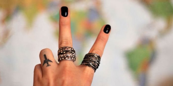 Tatuaggi sulle dita e una proposta con un aeroplano sul dito anulare di una donna