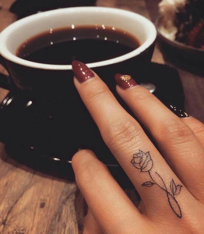 Tatuaggi piccoli sulle mani e un'idea con tattoo rosa sul dito di una donna