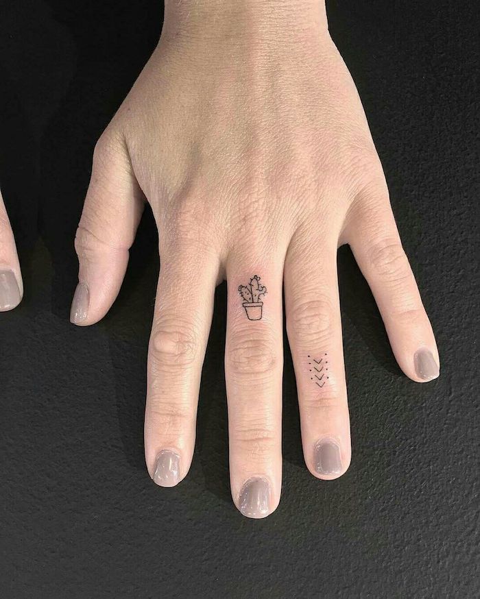 Idea per un tatuaggio sul dito di una donna con cactus e frecce con puntini