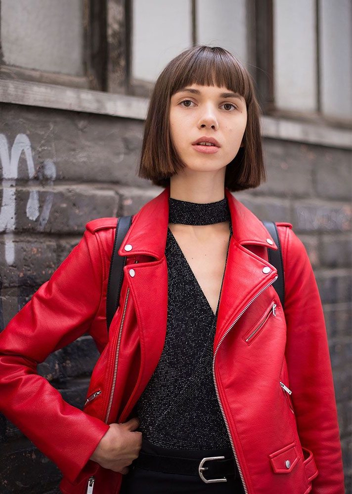 Nuovi tagli di capelli con frangia e carré medio corto pari, ragazza vestita con una giacca di pelle rossa