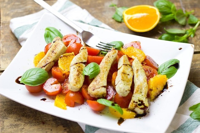 Idea per dieta nutrizionista con un piatto di pollo con contorno di pomodorini e foglie di basilico