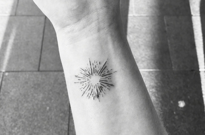 Il polso della mano di una donna tatuato con dei fuochi d'artificio 