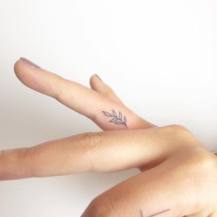 La mano di una donna con il tatuaggio di un fiore sul dito anulare