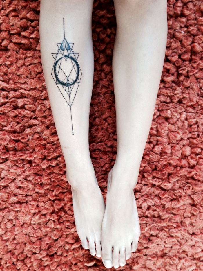 Idea per dei tatuaggi geometrici con tanti triangoli e un cerchio sulla gamba