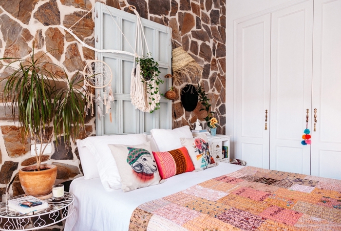 Camera da letto decorata con merletti e pizzi, parete con pietre a vista e armadio a muro