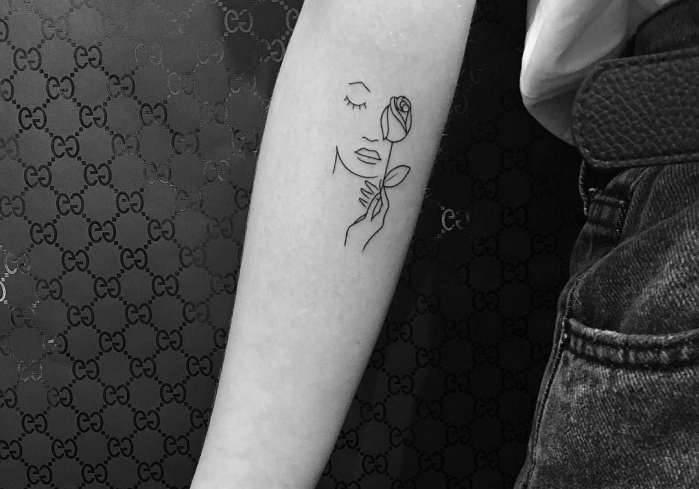 Tatuaggi piccoli significativi e un disegno di un viso femminile con una rosa in mano