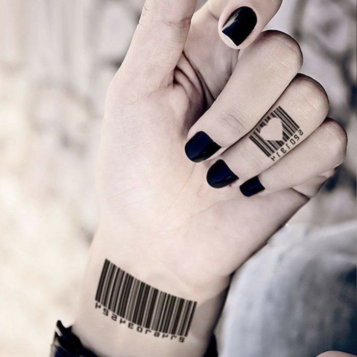 Mani tatuate e un'idea con tatuaggio sul polso e il dito anulare con cuore e numeri di barra