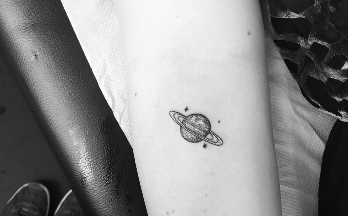 Tatuaggi discreti e un piccolo tattoo sul braccio di una donna con il disegno di un pianeta