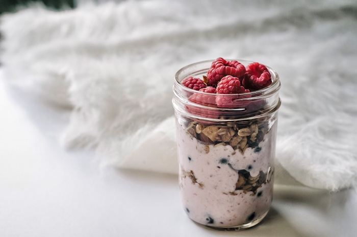 Alimentazione sana e un esempio per la colazione con yogurt, noci e aggiunta di lamponi