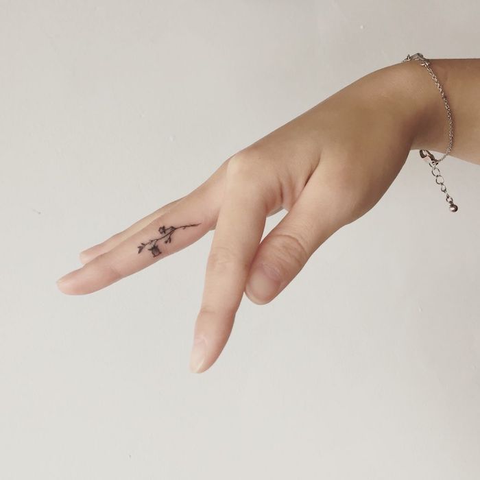Il dito medio di una donna con il tatuaggio di una piccola rosa